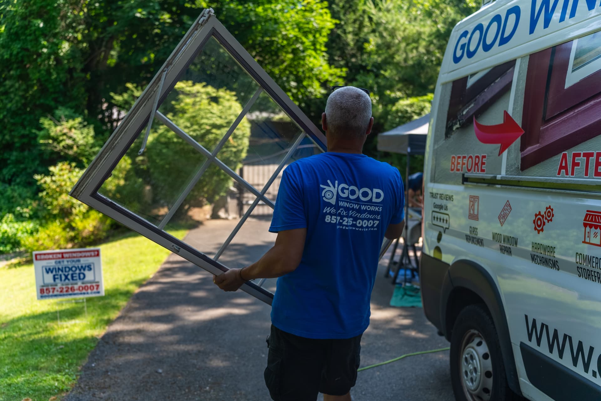 Good Window Works technician carrying a window sash to the service van